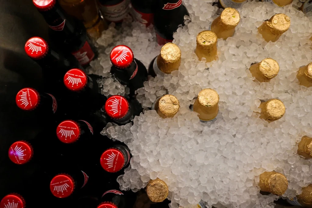 Overhead of Budweiser beer and foil-topped bottles in crushed ice.