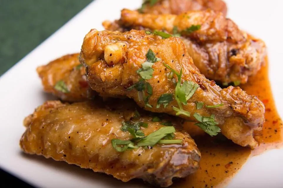 Close-up of glazed chicken wings with spices, herbs, and sauce.