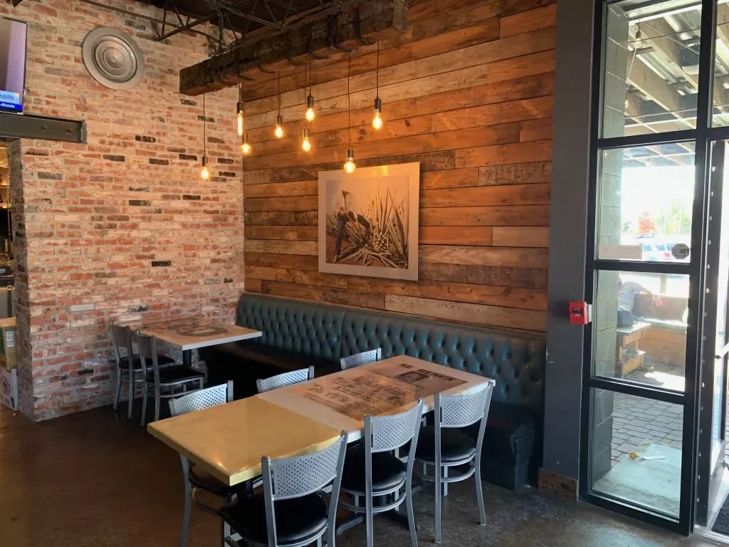 Restaurant interior: rustic-industrial design, teal booth, exposed brick, warm lights.