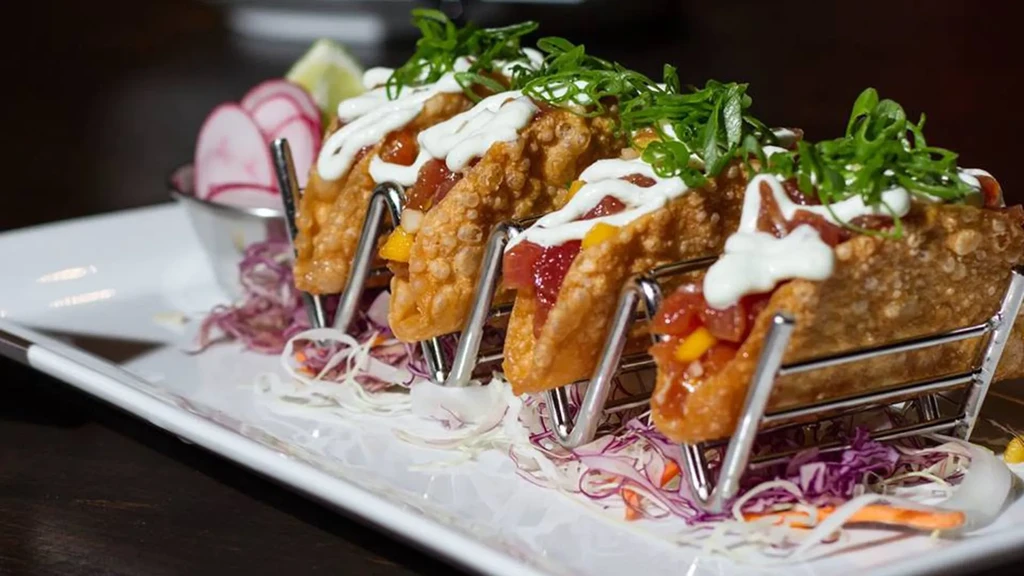 Four crispy tuna poke tacos with mango, sauce, and scallions.