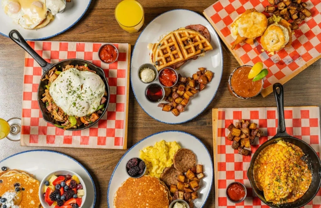Flat lay of diverse breakfast and brunch spread on wooden table.
