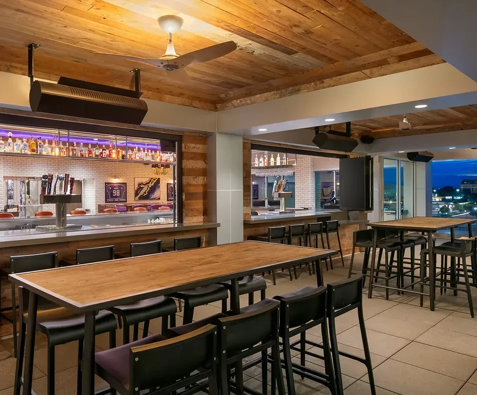 Empty rooftop bar interior, wood ceiling, brick, city lights.
