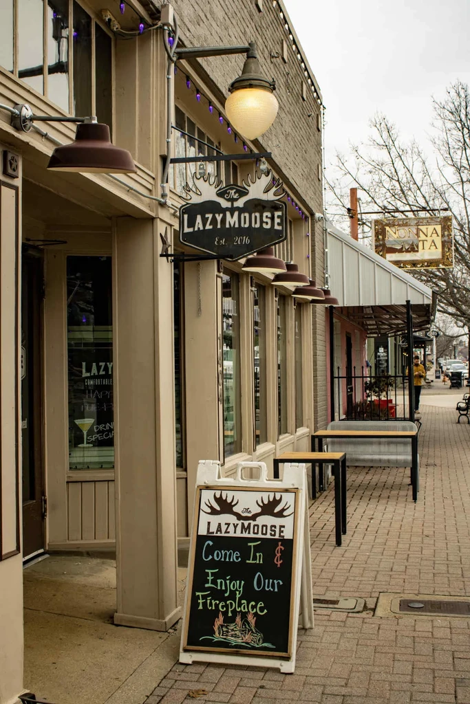 The Lazy Moose restaurant exterior, brick building, prominent sign, outdoor seating.