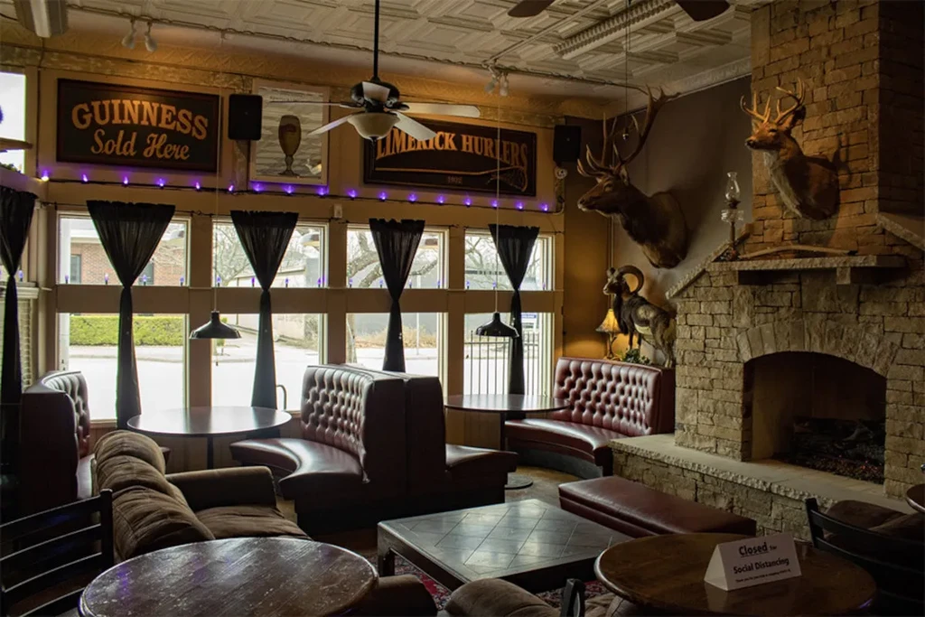 Rustic pub interior with stone fireplace, taxidermy, and "Closed" sign.