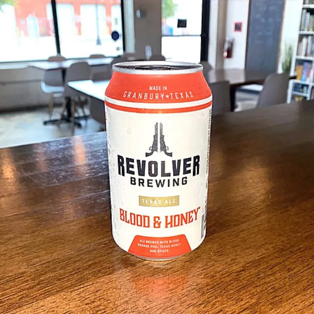Cold, condensation-covered Revolver Brewing ale can on wood.