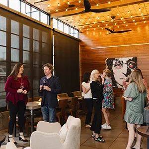 People socialize in a stylish, warmly lit restaurant with wood and art.