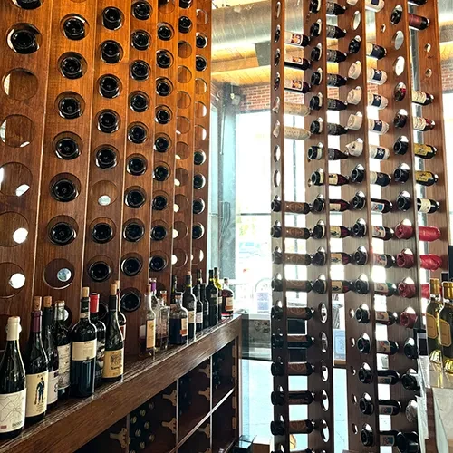 Multiple wooden wine racks filled with bottles in a restaurant interior.