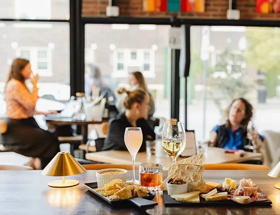 Charcuterie, dips, and drinks on a bar in a lively restaurant.