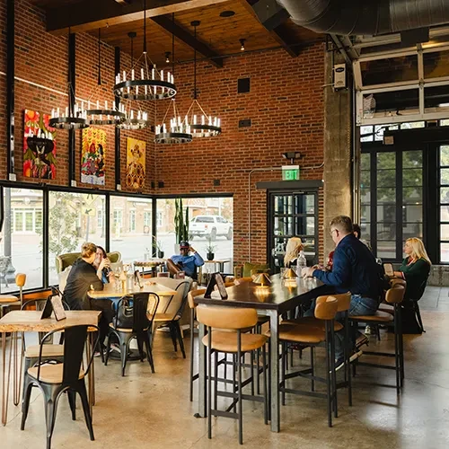Interior of industrial-chic restaurant with exposed brick, beams, and modern lighting.
