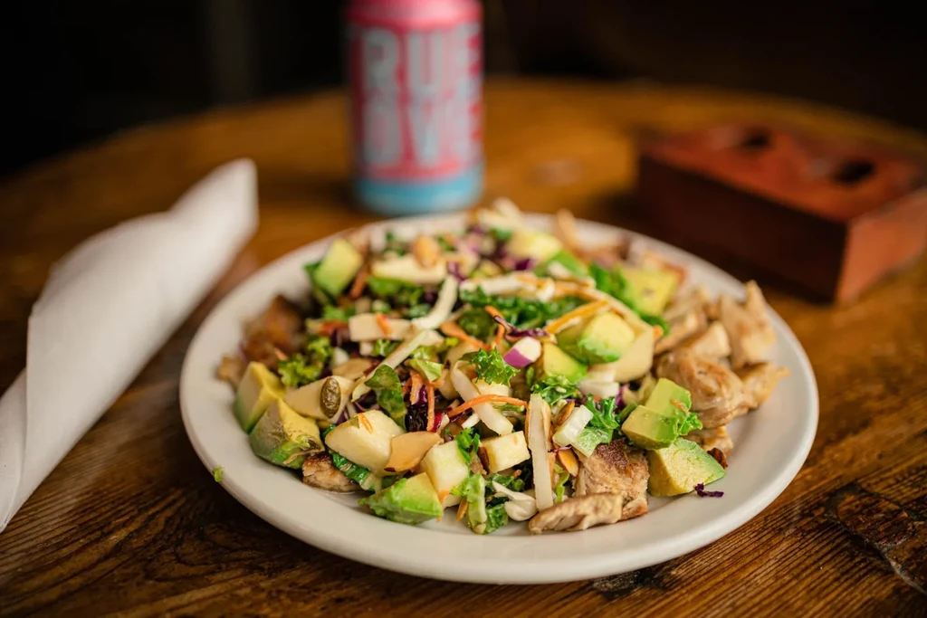 Colorful salad with grilled chicken, avocado, and mixed vegetables.