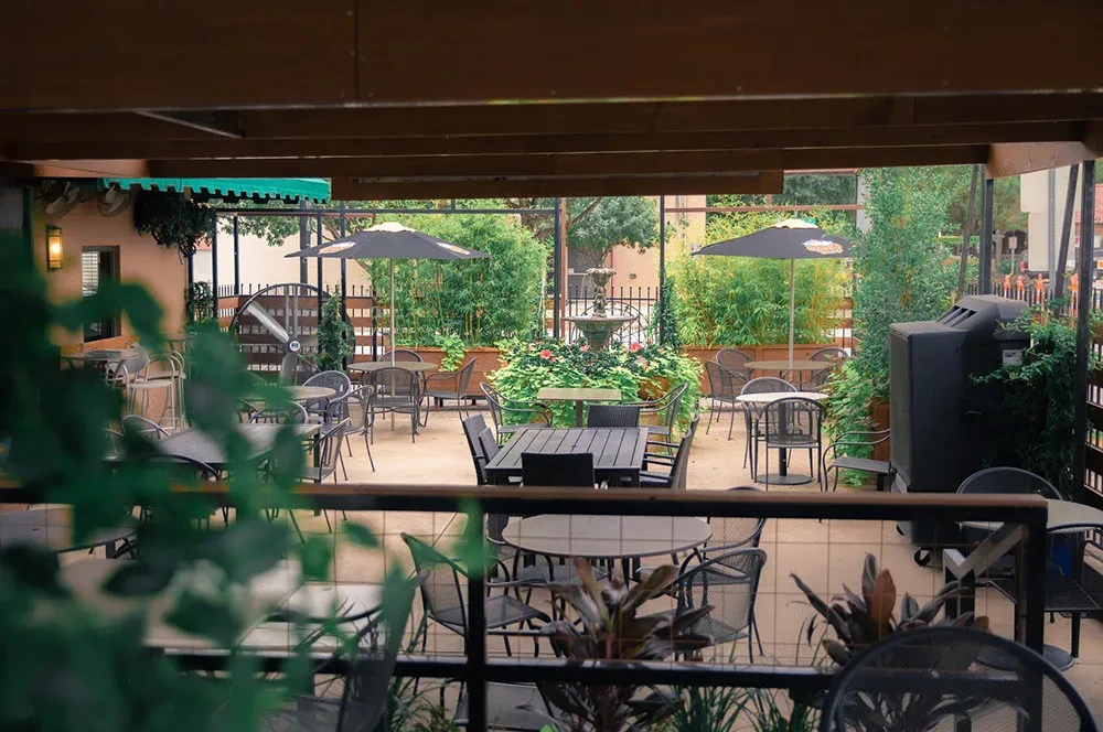 Outdoor patio with tables, chairs, umbrellas, water fountain, and BBQ.