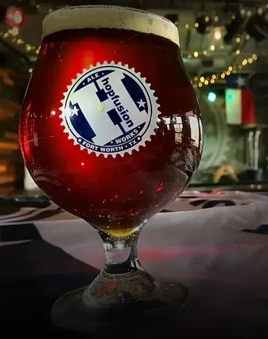 Stemmed glass of dark ale with a Hopfusion Works sticker.