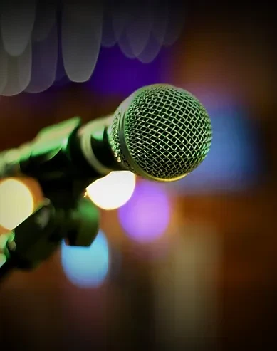 Detailed close-up of a green microphone's mesh head with colorful bokeh.