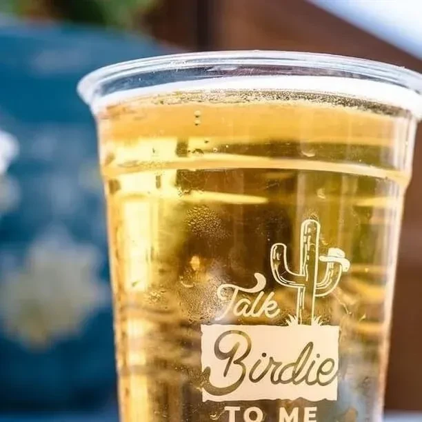 Cold golden drink in plastic cup with 'Talk Birdie' cactus.