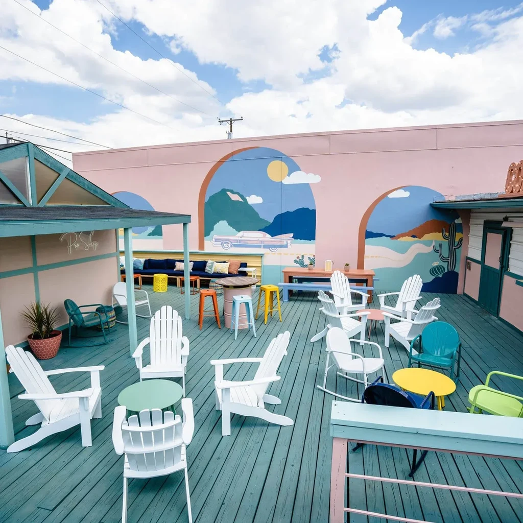 Colorful outdoor patio with turquoise deck and desert mural on pink wall.