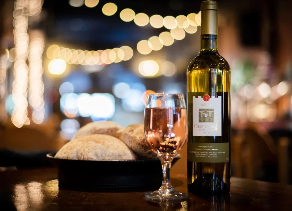 KSARA Chardonnay 2015, wine glass, and pita bread on a table.