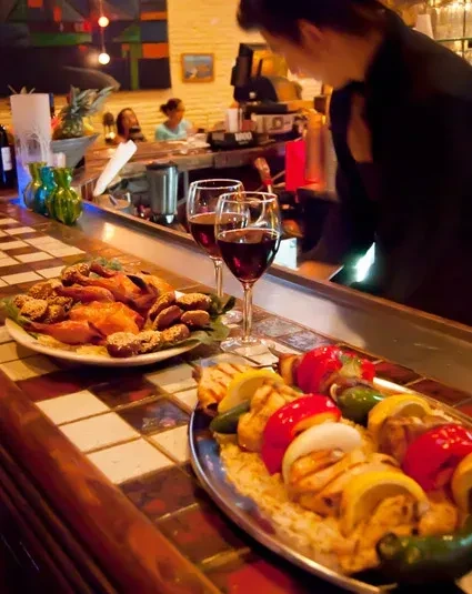 Roasted poultry, chicken kebabs, and red wine on a tiled bar.