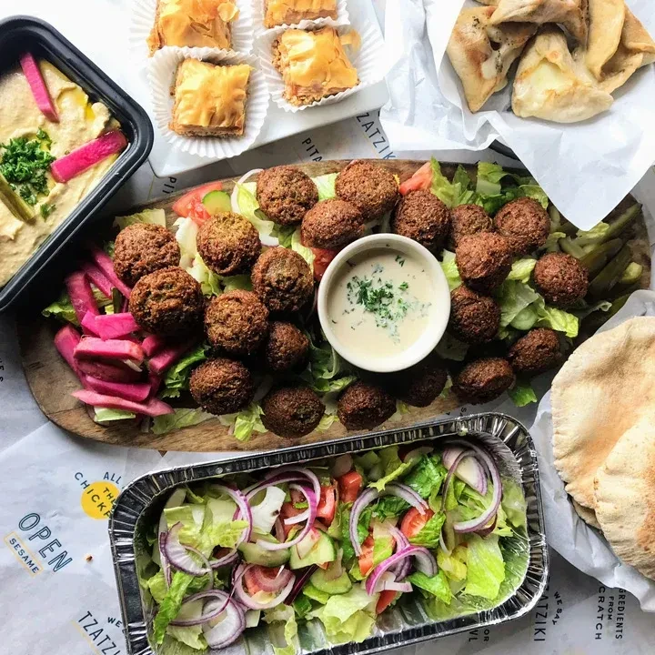 Middle Eastern falafel platter with hummus, pickles, baklava, and salad.