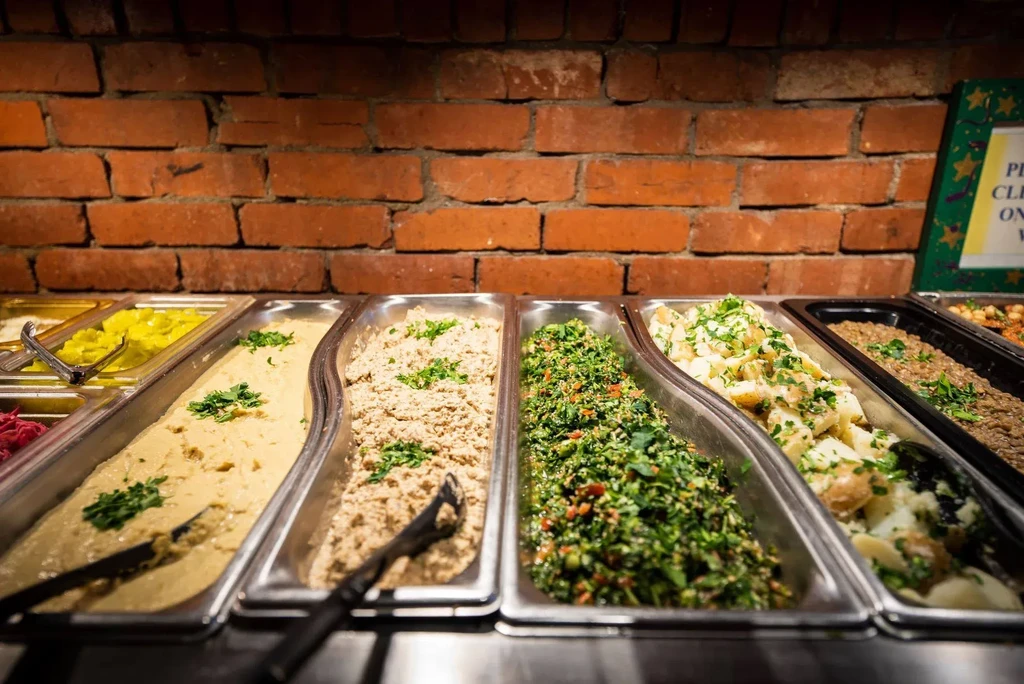 Buffet food display: various dishes in metal trays, topped with fresh herbs.