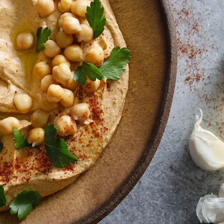 Hummus topped with chickpeas, spice, parsley, and olive oil.