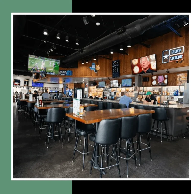 Casual sports bar interior with high-top tables, a bar, and TVs.