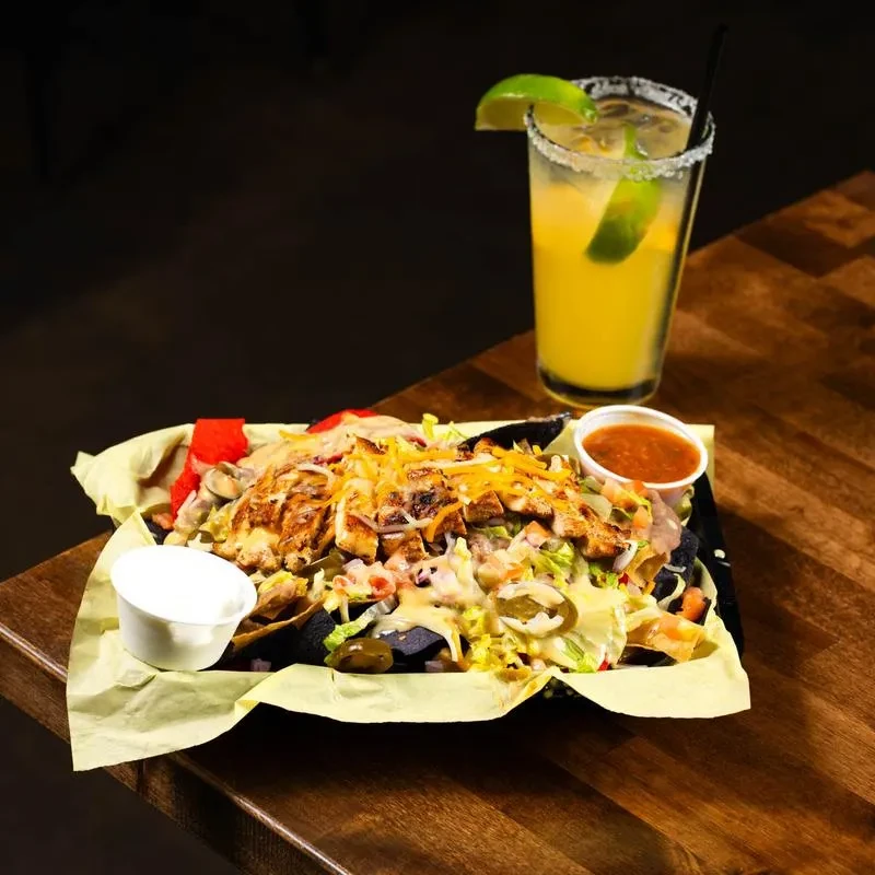 Grilled chicken nachos with cheese, jalapeños, and a lime margarita.
