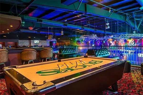 Vibrant, dimly lit bar with 'BUCKS' pool table and colorful lights.