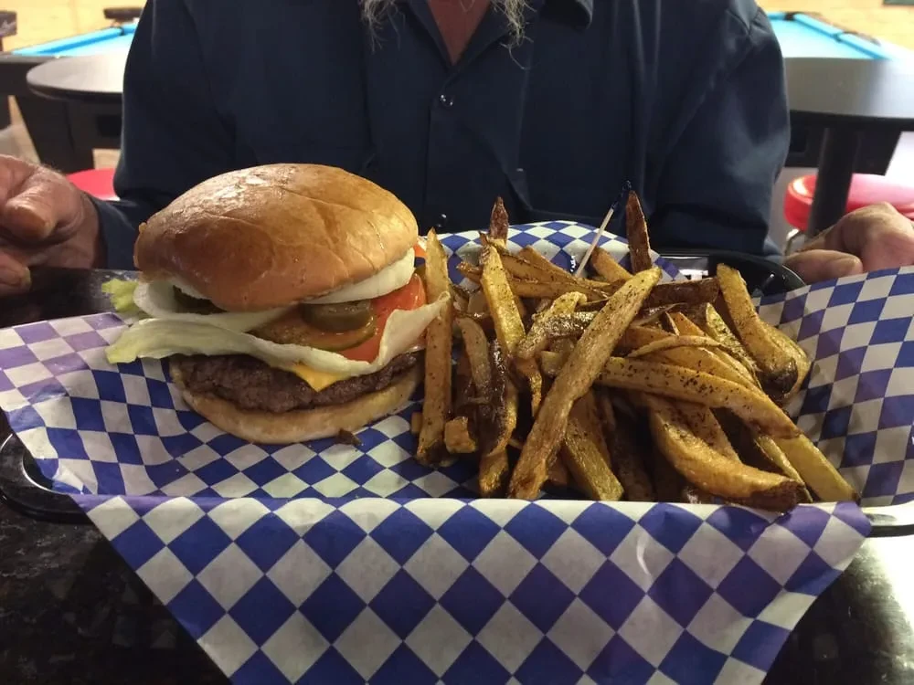 Double cheeseburger with jalapenos, seasoned fries, served in a black basket.