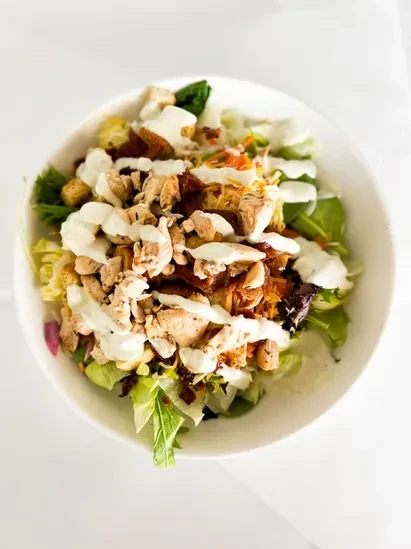 Close-up of chicken salad with mixed greens, croutons, and creamy dressing.