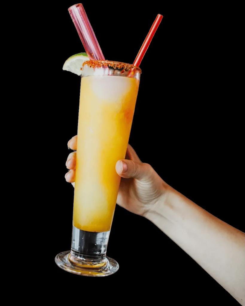 Frothy orange drink with a chili-salted rim, lime, and straws.
