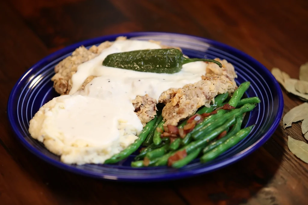 Chicken fried steak, mashed potatoes, green beans, jalapeño on blue plate.
