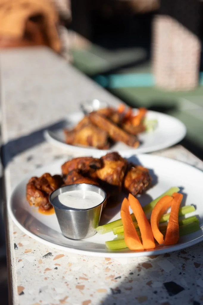 Golden chicken wings, white dipping sauce, carrot and celery sticks.