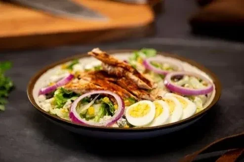 Vibrant salad with grilled chicken, eggs, red onion, blue cheese.