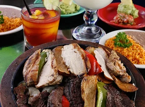 Sizzling chicken and steak fajitas, rice, beans, salsa, guacamole, drinks.
