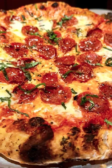 Overhead close-up: pepperoni pizza with melted cheese and fresh herbs.