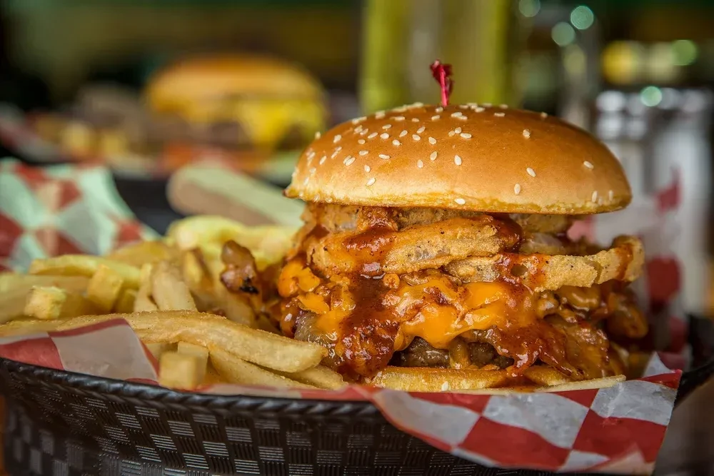 A gourmet hamburger and french fries served in a checkered basket.