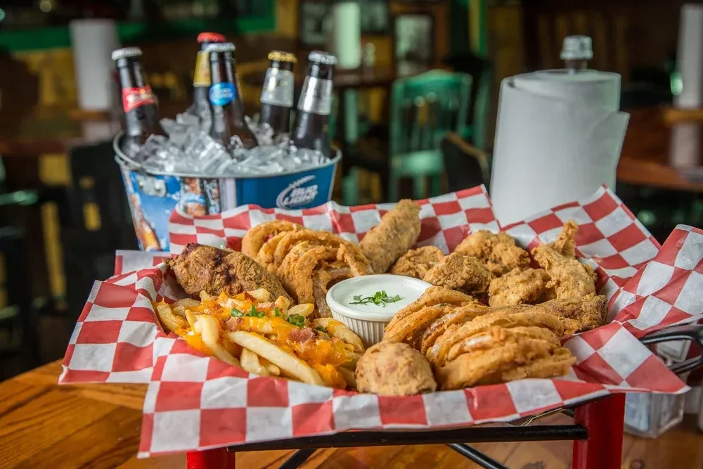 Platter of fried chicken, onion rings, loaded fries, and dipping sauce.