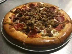 Rustic round pizza with thick crust, sausage, pepperoni, and melted cheese.