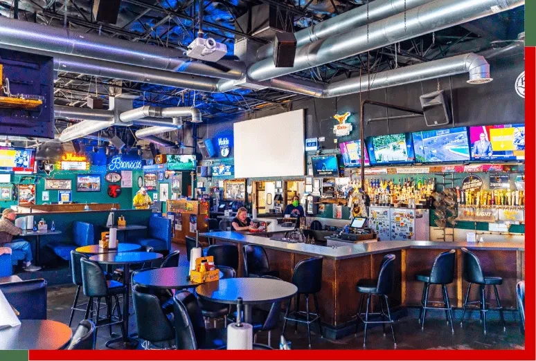 Vibrant sports bar with blue booths, long bar, and many TVs.