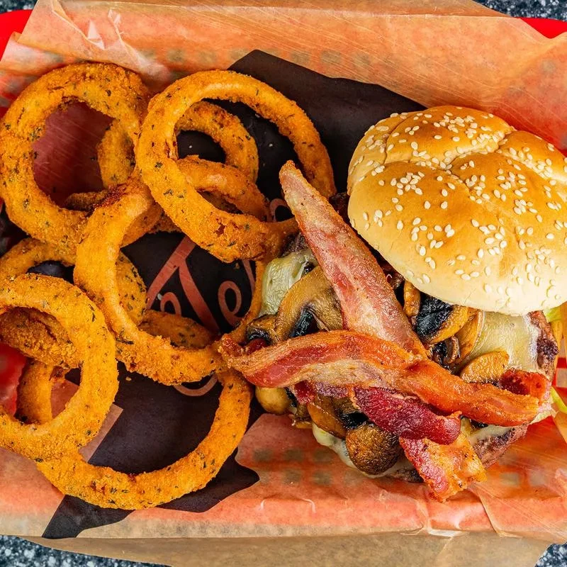 Loaded burger with bacon, cheese, mushrooms, and seasoned onion rings.