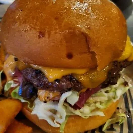 A juicy burger with melted cheese, fresh greens, and potato wedges.