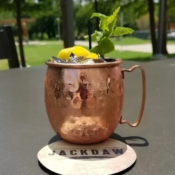 Cold copper mug with drink, lemon, mint, straw on JACKDAW coaster.