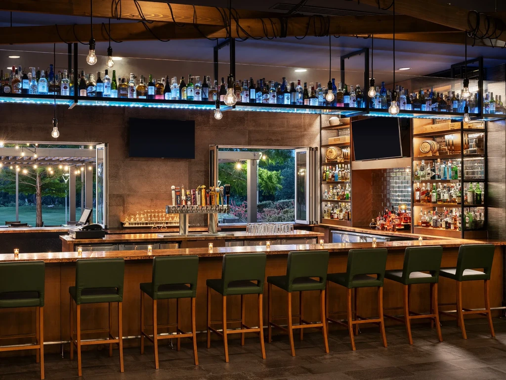 Modern bar with blue LED-backlit liquor bottles and open patio.