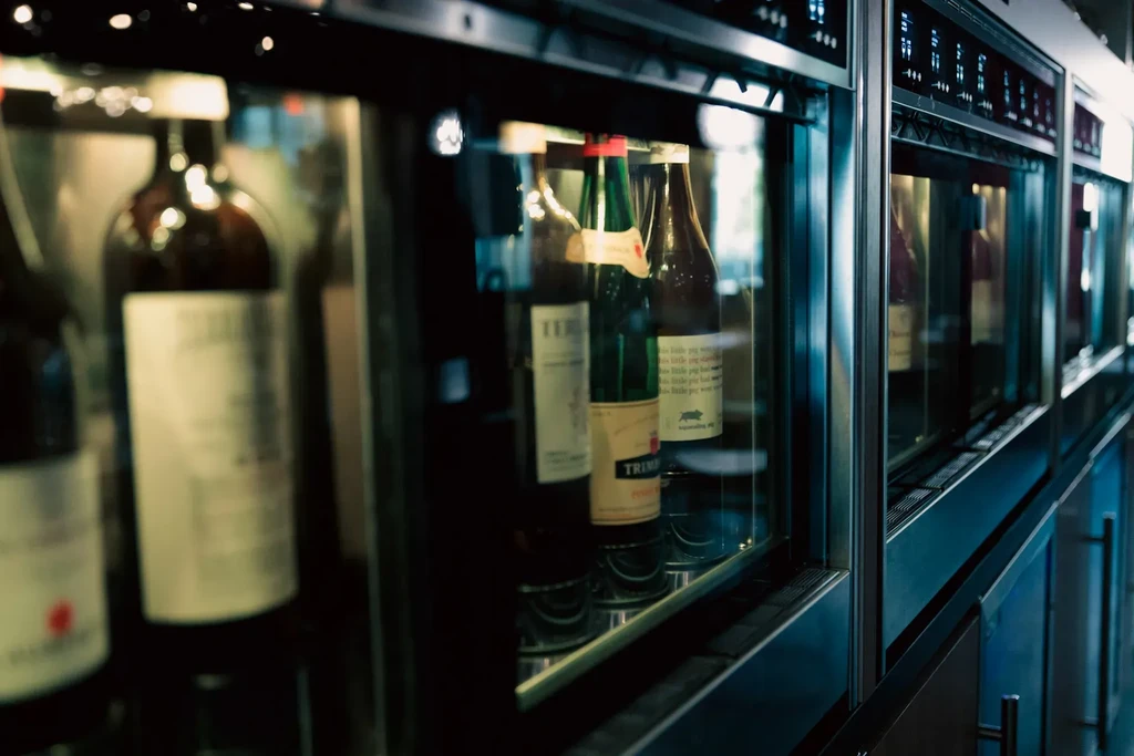 Modern refrigerated unit displaying various wine and craft beer bottles.