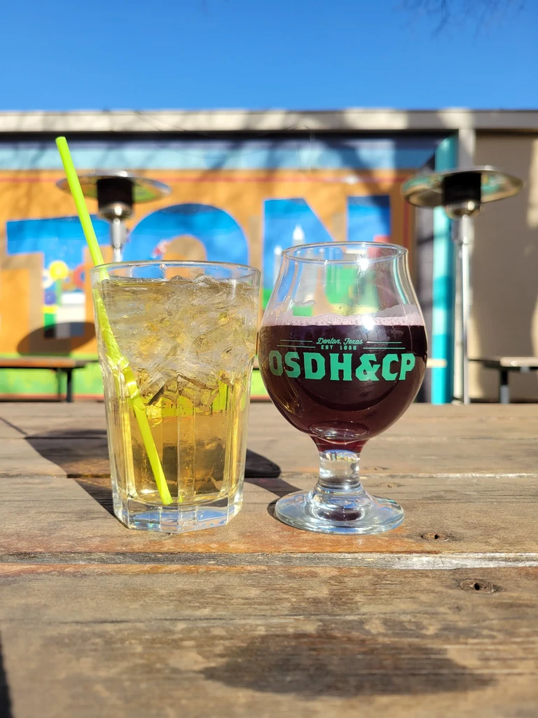 Yellow and red drinks on wooden table with "Denton, Texas" text.