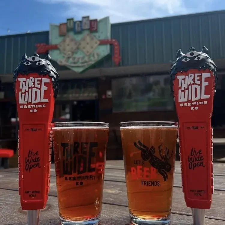 Three Wide Brewing Co beers and branded tap handles outdoors.