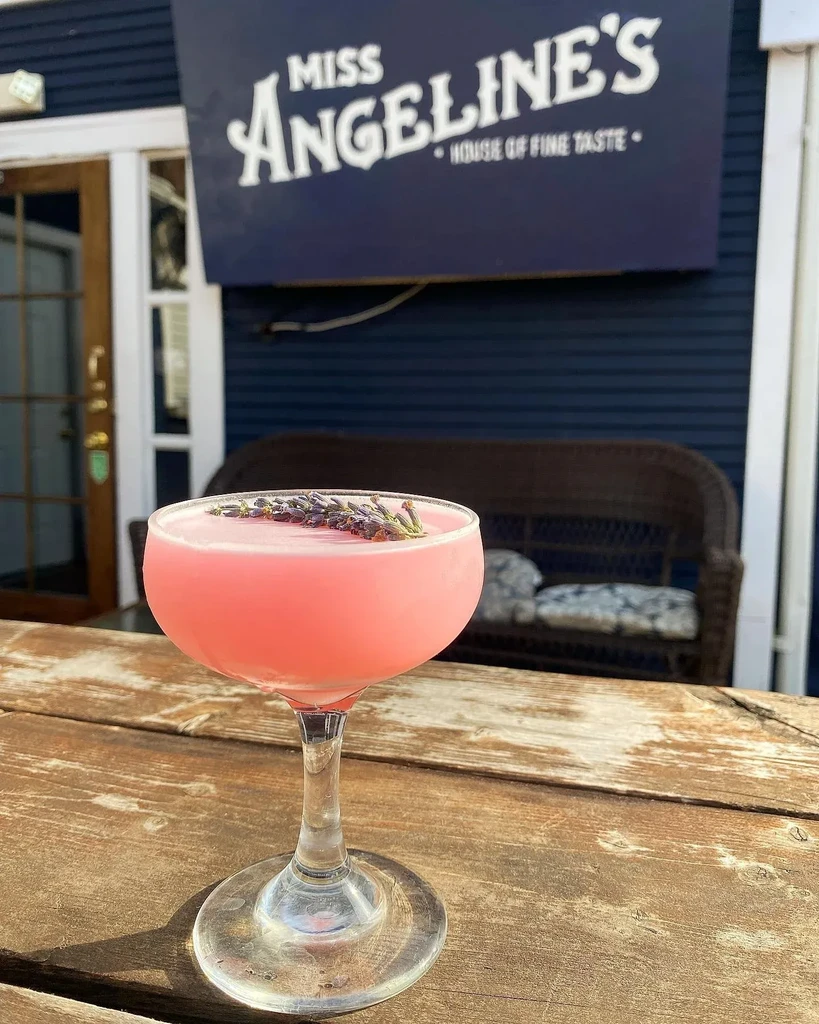 Pink lavender cocktail on wood table outside Miss Angeline's.