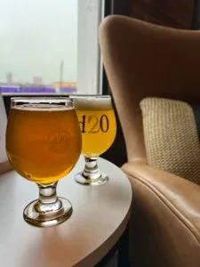 Two stemmed glasses with amber liquid, one etched H2O, on a table.