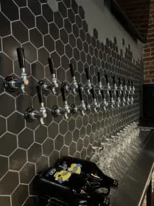 Beer taps on hexagonal tiled wall, polished counter with growlers.