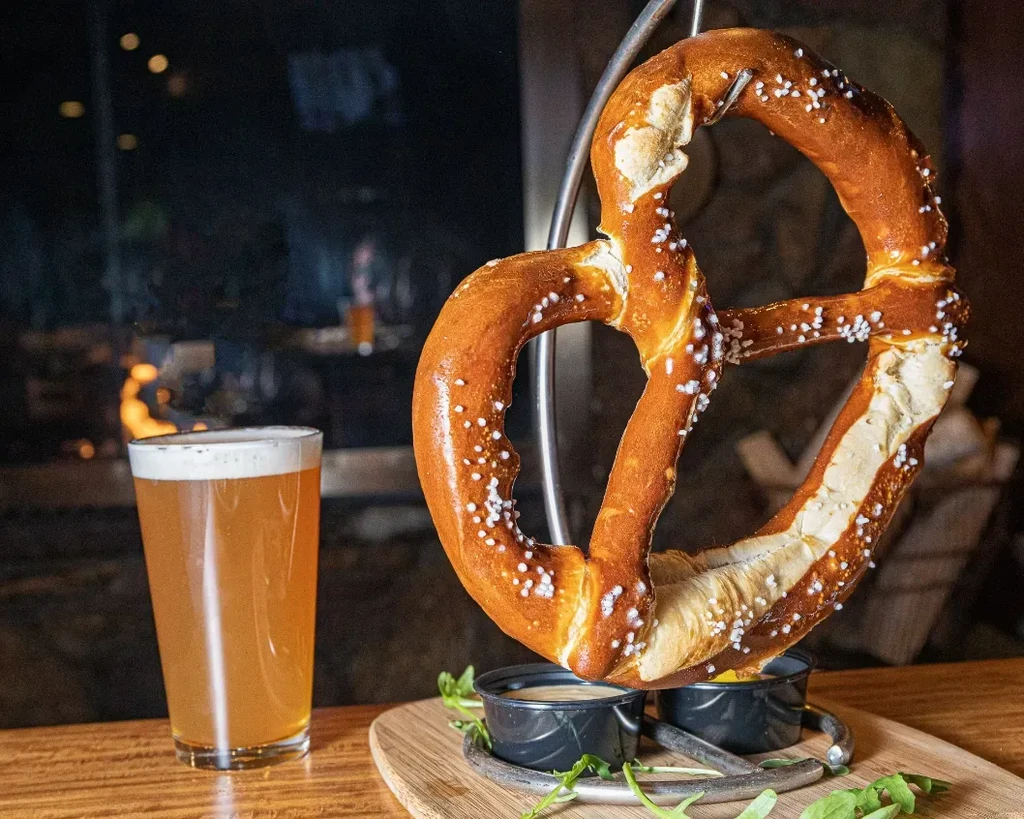 Salted soft pretzel, amber beer, and condiment cups.